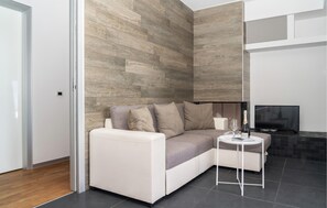 A modern living room with a sectional sofa, a small side table, a television, and a dark tiled floor. - 2 bedroom gorgeous apartment in Porto Cesareo (Porto Cesareo)
