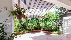 Une serre abritant diverses plantes et fleurs, dotée d’un sol carrelé et d’un toit en verre.