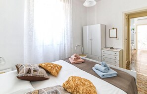 A hotel room with a bed, a bedside table, a wardrobe, and a bathroom visible through an open door. - Cozy home in S. Maria del Focallo with WiFi (S. Maria del Focallo)