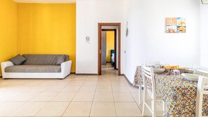 A room with a sofa, a dining table with chairs, and a door leading to another room. - 2 bedroom stunning apartment in Scicli (Scicli)