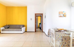 A room with a sofa, a dining table with chairs, and a door leading to another room. - 2 bedroom stunning apartment in Scicli (Scicli)