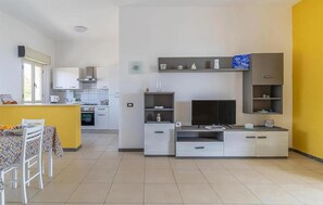 A modern kitchen with a built-in TV, a dining area with a table and chairs, and a yellow accent wall. - 2 bedroom stunning apartment in Scicli (Scicli)