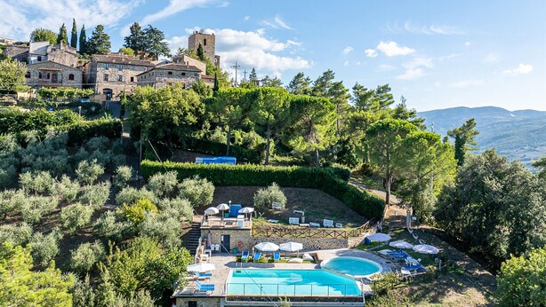 Un resort con piscina, lettini e vista su un edificio storico.