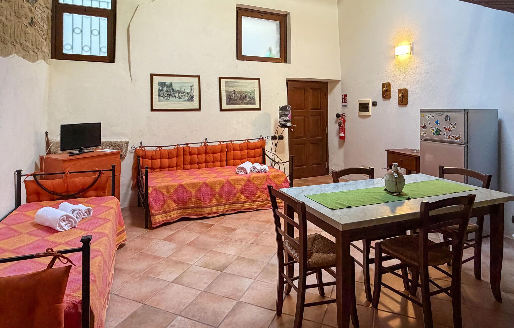 Una habitación con una cama, una mesa con sillas, un televisor y una puerta.