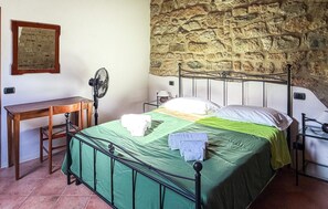 A bedroom with a stone wall, a metal bed frame, a desk, and a chair. - Awesome apartment in Montecastelli Pisano (Montecastelli Pisano)