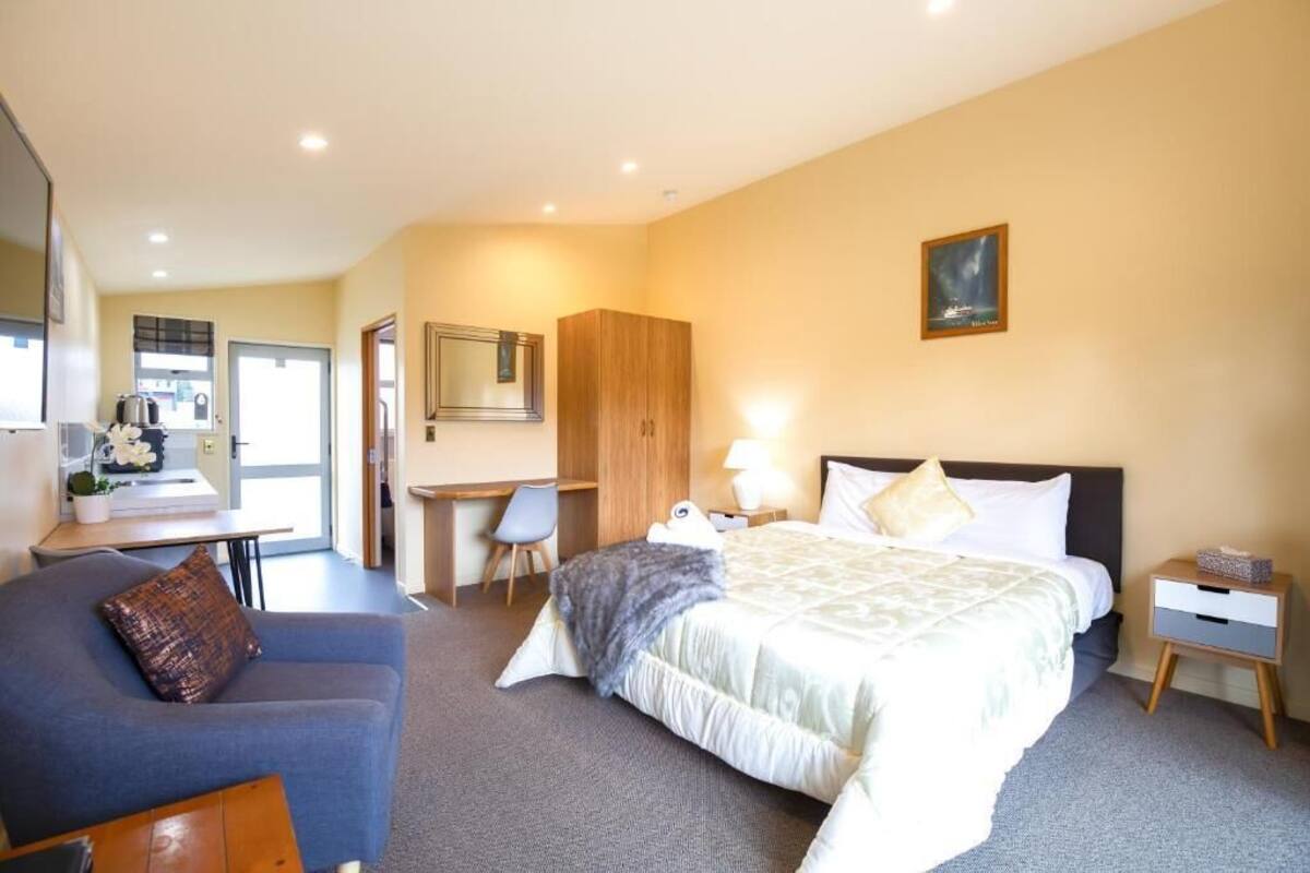 Una habitación de hotel con cama, escritorio, silla, sofá y armario.