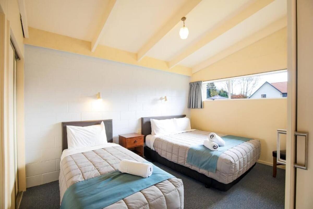 Habitación de hotel con dos camas, una ventana y vistas al exterior.