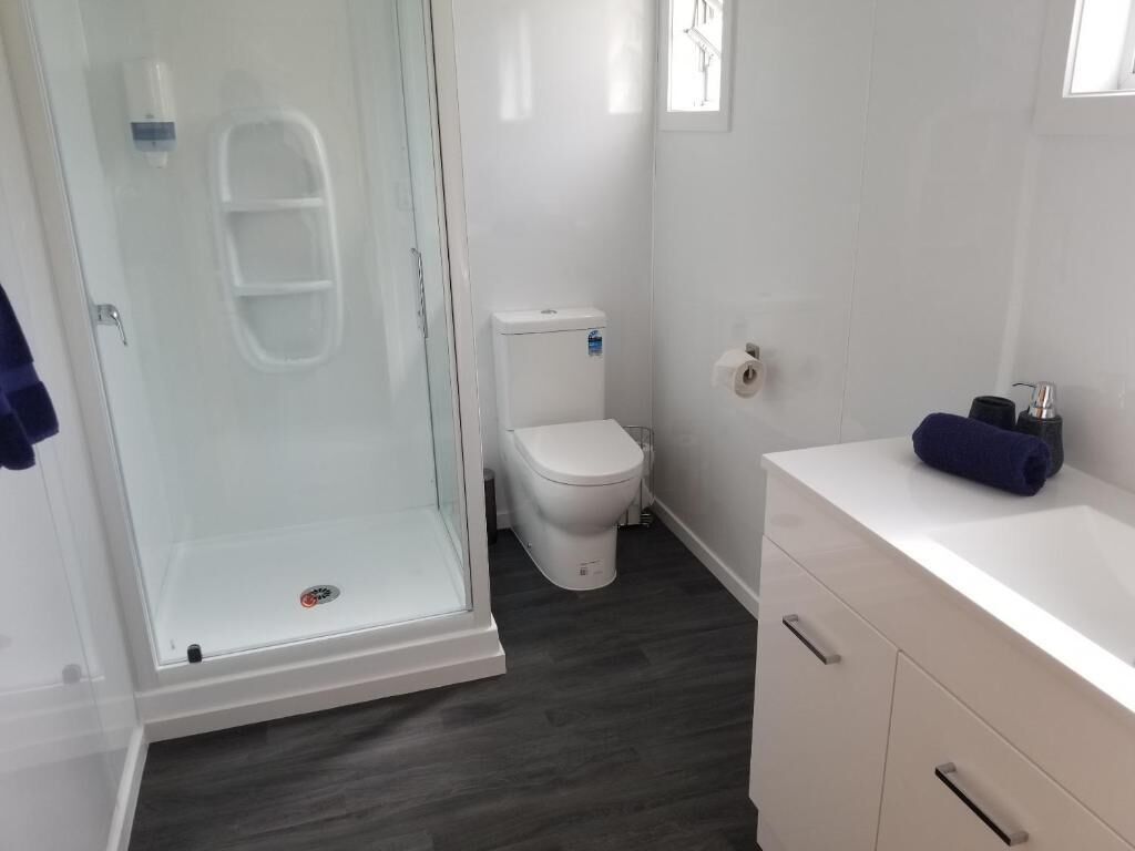 A bathroom with a glass-enclosed shower, a white toilet, and a white vanity with a towel.