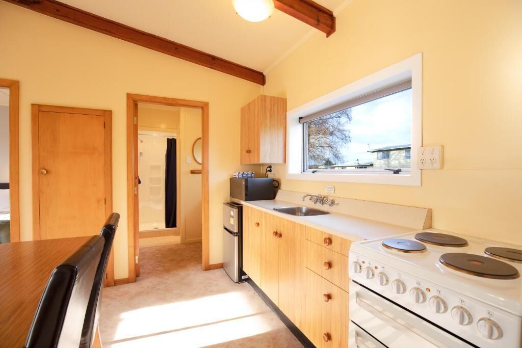 A kitchen with wooden cabinets, a stove, and a window.