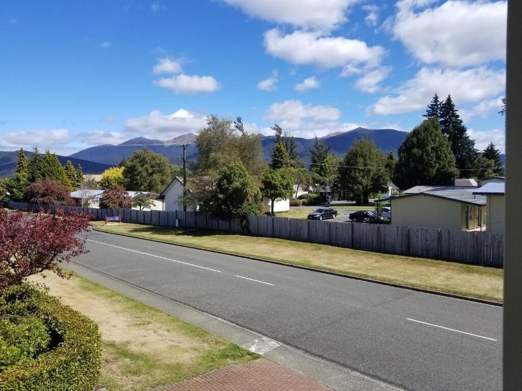 Una calle residencial con casas, cielo despejado y montañas al fondo.