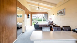 A room with a bed, a sofa, a dining table, and a view of the outdoors.