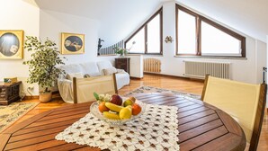Een gezellige woonkamer met een houten tafel, een fruitschaal, een potplant en een bank.