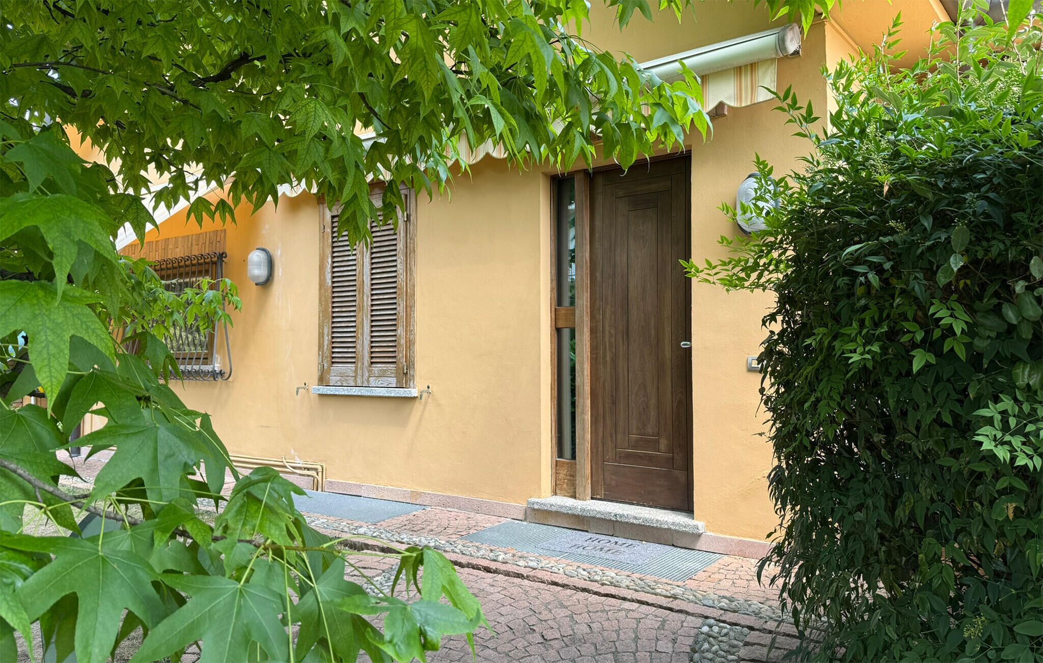 Ein Gebäude mit einer braunen Tür, einem Fenster mit Fensterläden und einem kleinen Fenster mit einer Lampe.
