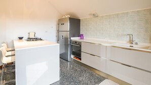 Een moderne keuken met een wit aanrecht, roestvrijstalen apparatuur en een betegelde spatwand.