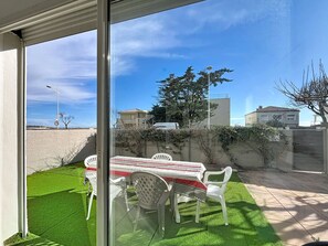 A patio with a table and chairs, a view of the street, and a clear sky. - Bright apartment, parking, 9 guests (Mauguio)