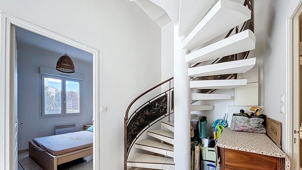 A bedroom with a bed, a window, and a staircase.