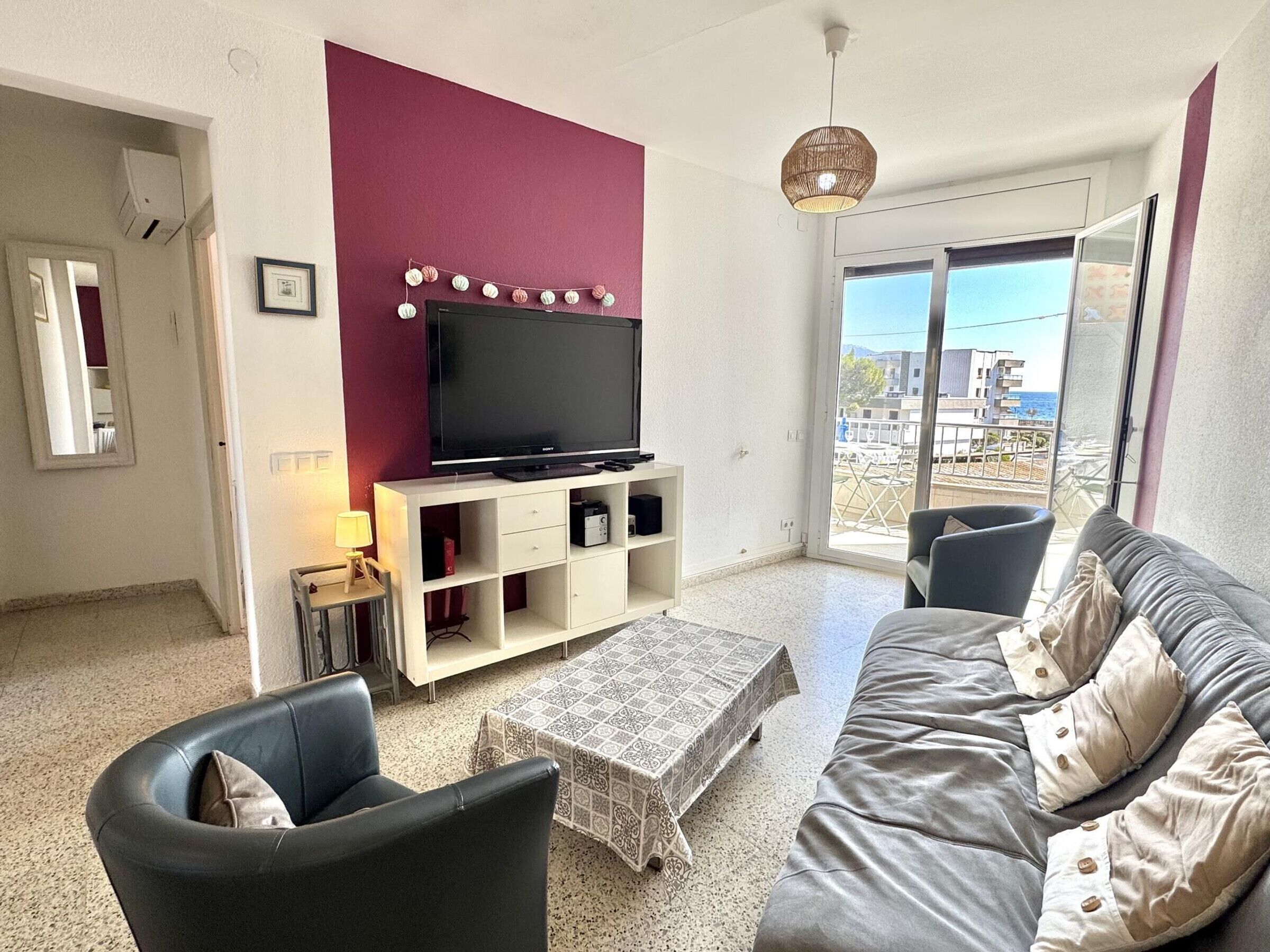 Een woonkamer met een flatscreen-tv, een bank, een salontafel en uitzicht op het omliggende gebied.