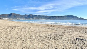 Una spiaggia con una montagna sullo sfondo e un cielo sereno.
