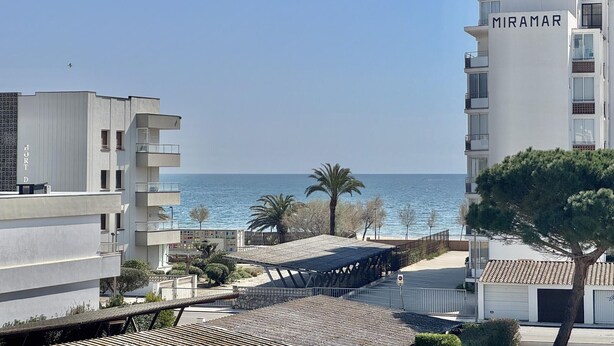 Un edificio costiero chiamato MIRAMAR con balconi, vista sul mare e un'area di parcheggio.