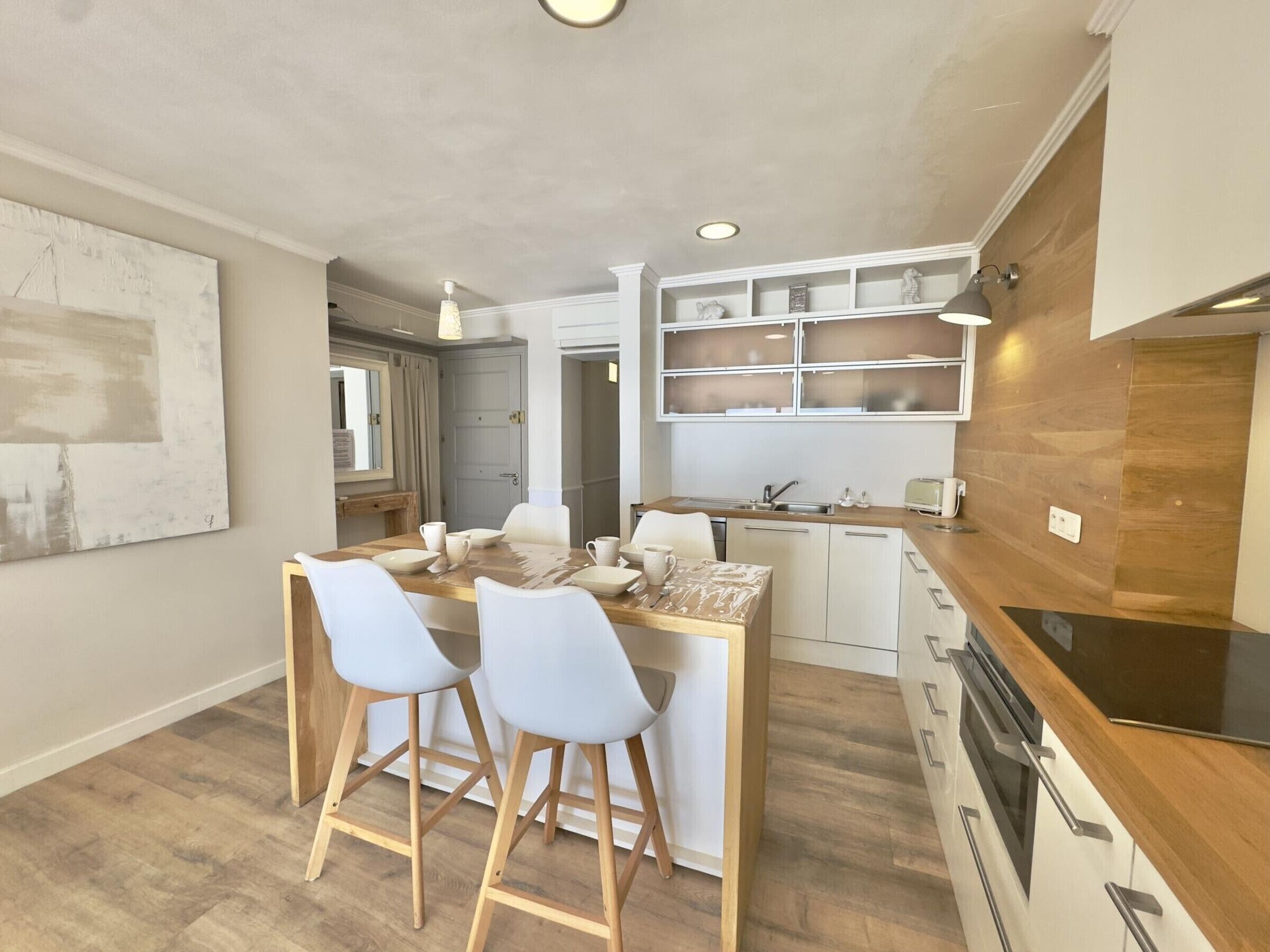 A modern kitchen with a wooden island, bar stools, and built-in shelves.