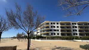 Un immeuble à plusieurs étages doté de balcons, d’une allée pavée et d’arbres.