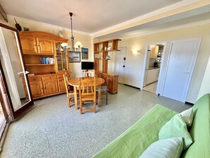 A dining area with a wooden table and chairs, a chandelier, and wooden cabinets. - 3-bedroom seafront apartment with parking in Roses (Roses)