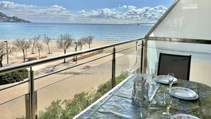 Un balcon avec une table dressée pour le dîner, offrant une vue sur la plage et la mer.