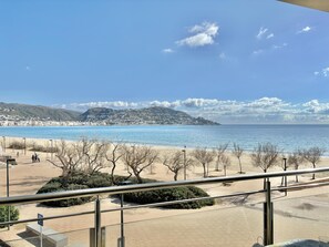Une vue sur la côte, avec une plage, une promenade et des collines à l’horizon.