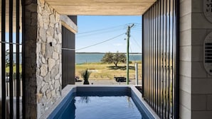 A stone wall, a pool, and a view of the water.