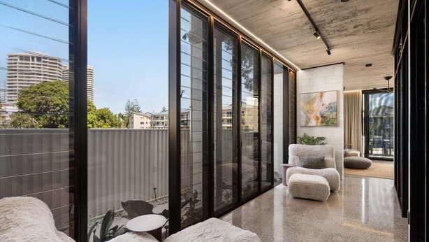A modern interior with large windows, a polished floor, and a seating area with a view of the city.