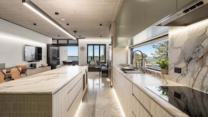 A modern kitchen with a large island, built-in appliances, and a view to the outdoors.