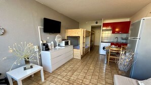 A compact living space with a kitchenette, a dining area, and a TV mounted on the wall. - Practical studio cabin near beach - 4 guests (Cap d'Agde)