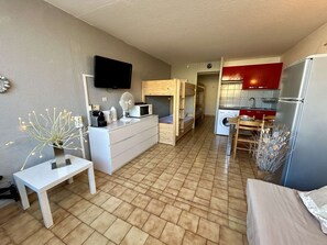 A compact living space with a kitchenette, a dining area, and a TV mounted on the wall. - Practical studio cabin near beach - 4 guests (Cap d'Agde)