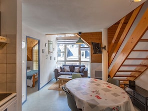 A compact room with a bed, a sofa, a table, and a staircase. - Charming apartment, mountain view - 4 guests (Cauterets)