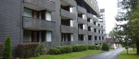 En flere etagers boligbygning med altaner og en belagt indkørsel.