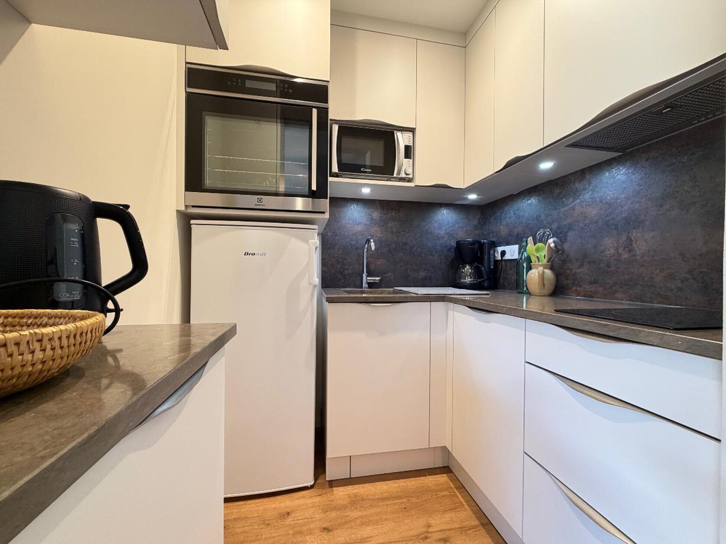 Una cocina moderna con horno integrado, microondas y cafetera.