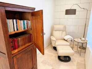 A room with a wooden bookshelf, a leather armchair, a small table with a teapot, and a floor lamp. - Cottage with air conditioning - 9 guests (Le Louroux)