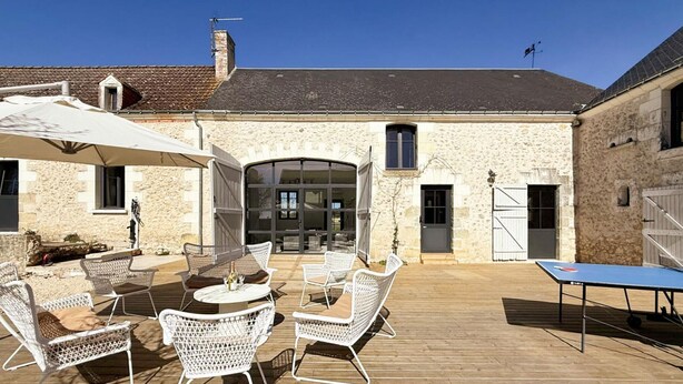 Un bâtiment en pierre doté d’un patio comprenant un espace extérieur avec des sièges et une table de ping-pong.