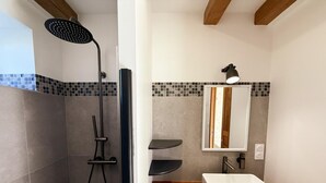 Ein Badezimmer mit Dusche, Waschbecken, Spiegel und Fliesen an der Wand.