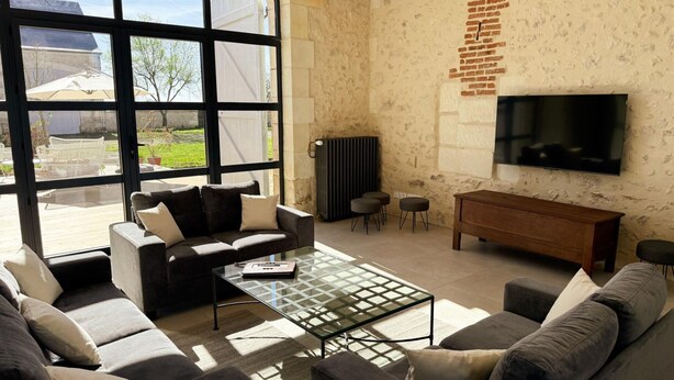 Ein Wohnzimmer mit großem Fenster, Flachbildfernseher, einer Couch, einem Couchtisch und einer Heizung.