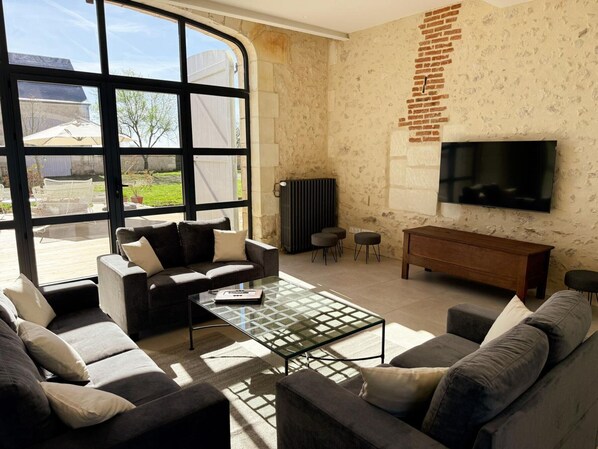 Ein Wohnzimmer mit großem Fenster, Flachbildfernseher, einer Couch, einem Couchtisch und einer Heizung.