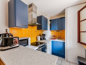 A compact kitchen with a toaster, microwave, stove, and blue cabinets. - Charming apartment in greenery - 4 guests (Arcachon)