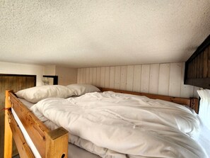 A single bed with white bedding in a room with wooden paneling on the walls and ceiling. - Studio with balcony, pets welcome - 4 guests (Samoëns)