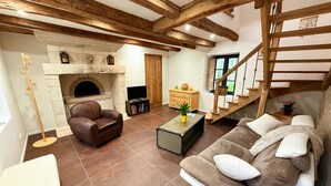 Un salon avec une cheminée, un canapé, une table basse, un téléviseur et un escalier.