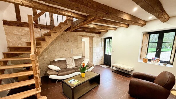 Un vaste espace de vie agrémenté d’un escalier en bois, d’un canapé, d’une table basse et d’une fenêtre offrant une vue agréable.