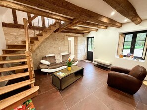 Un vaste espace de vie agrémenté d’un escalier en bois, d’un canapé, d’une table basse et d’une fenêtre offrant une vue agréable.