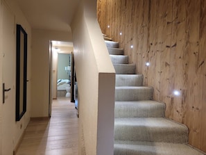 Ein Flur, der zu einem Schlafzimmer mit einer Holztreppe führt.