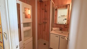 Un baño con ducha, lavamanos, espejo y toallero.
