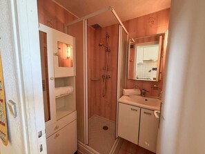 Ein Badezimmer mit Dusche, Waschbecken, Spiegel und Handtuchhalter.