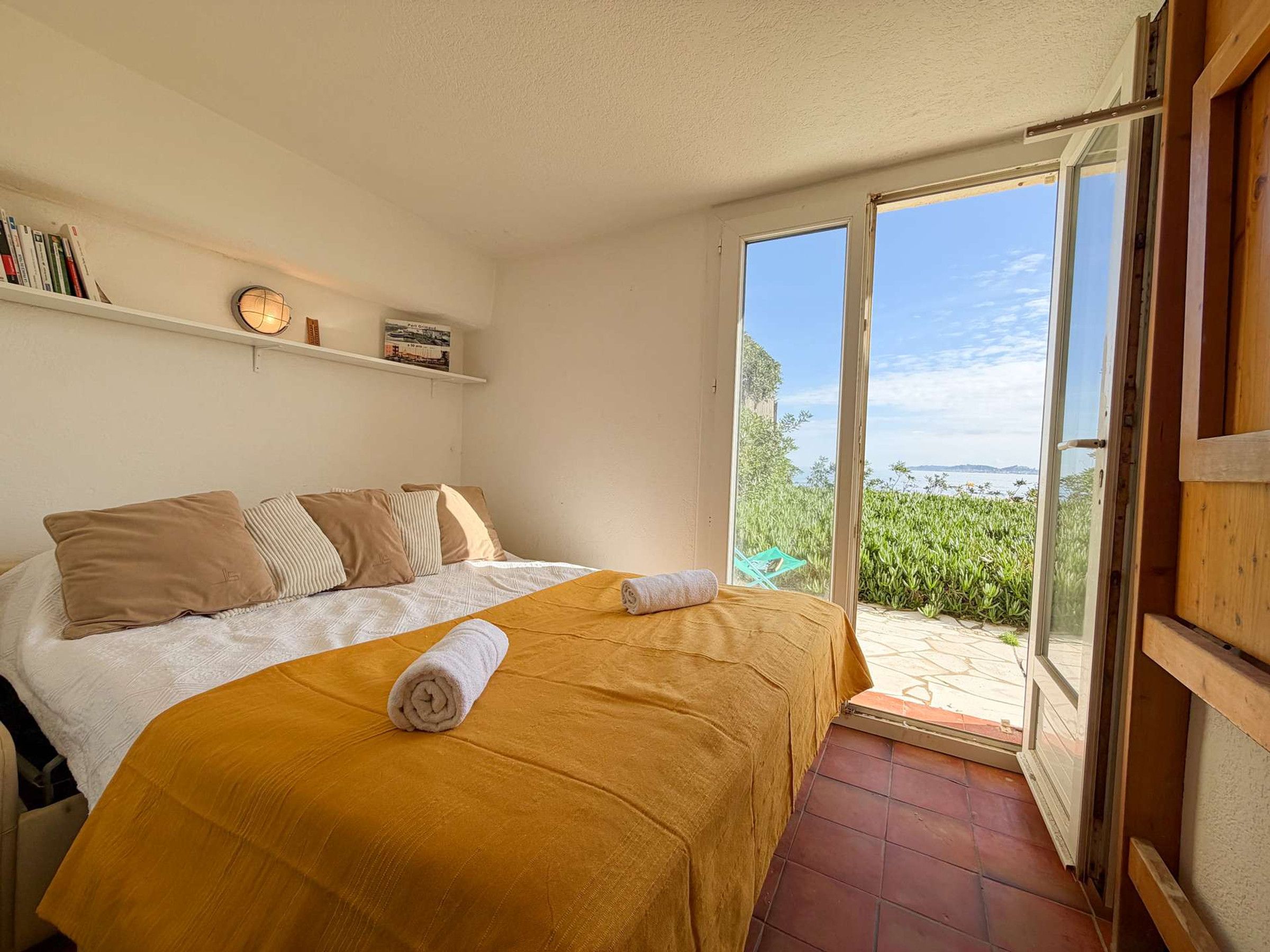 A bedroom with a bed, a window, and a view of greenery.